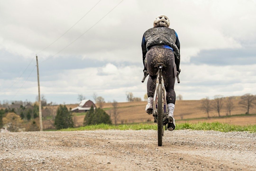 Cyclist riding a mud-covered gravel bike on a rural gravel road